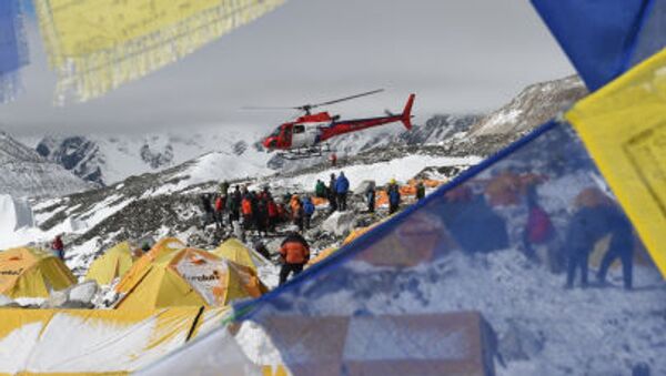 Поисковый вертолет, в обрамлении флагов с молитвами в Непале, забирает пострадавших после землетрясения из лагеря Everest Base Camp - Sputnik Молдова