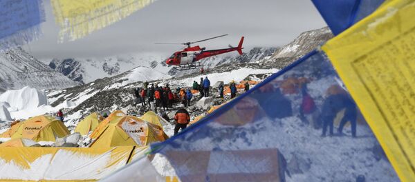 Поисковый вертолет, в обрамлении флагов с молитвами в Непале, забирает пострадавших после землетрясения из лагеря Everest Base Camp - Sputnik Молдова