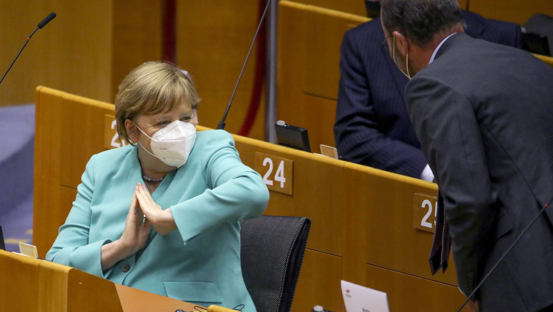 Канцлер Германии Ангела Меркель во время приветствия локтем на пленарной сессии Европейского парламента в Брюсселе  - Sputnik Moldova-România, 1920, 28.03.2021