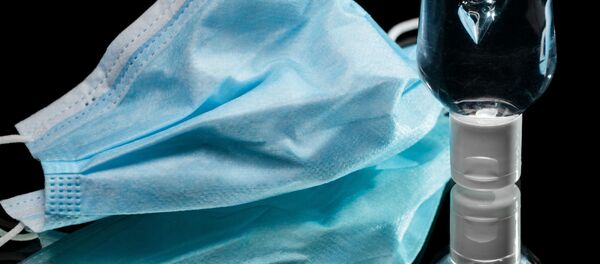 Защитная маска рядом с бутылкой с антибактериальным гелем - Sputnik Moldova