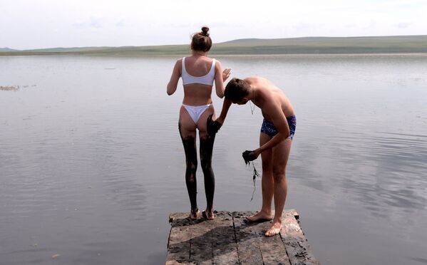 Мужчина намазывает девушку сульфидной грязью из озера Тус в Ширинском районе Республики Хакасия - Sputnik Молдова