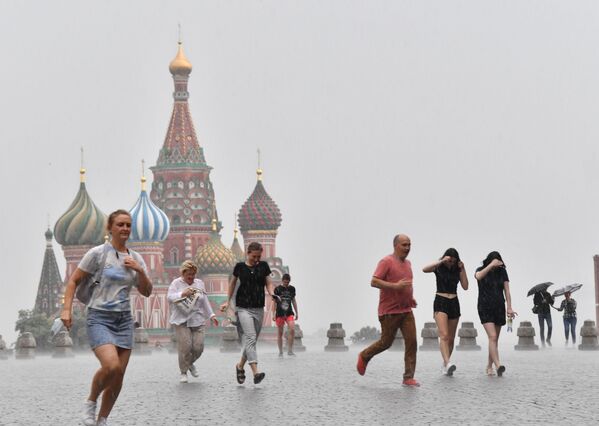 Люди под проливным дождем на Красной площади в Москве - Sputnik Молдова