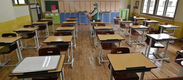 Un muncitor pulverizează dezinfectant într-o sală de clasă la un liceu din Seul - Sputnik Moldova-România