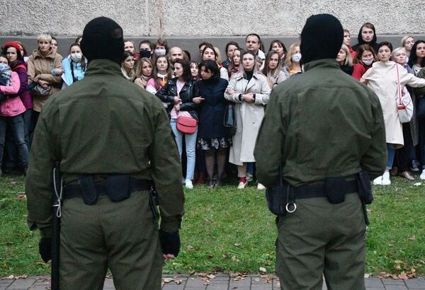 Люди в камуфляжной форме стоят напротив участников акции протеста в Минске - Sputnik Молдова