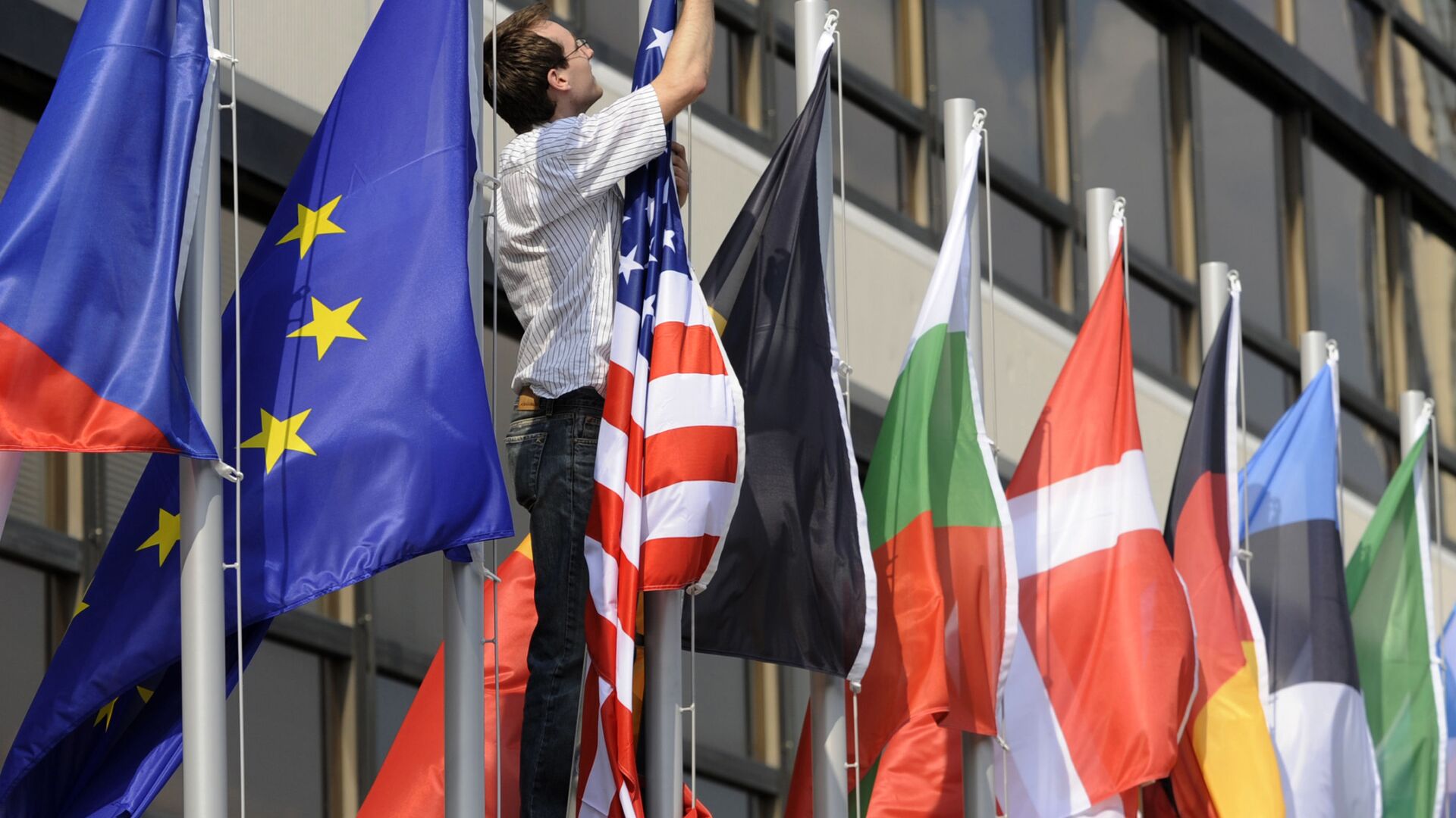Сотрудник вешает флаг США между флагами стран Евросоюза - Sputnik Молдова, 1920, 15.06.2021