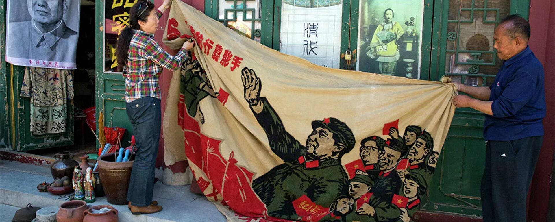 Продавцы разворачивают плакат 1969 года с изображением бывшего китайского лидера Мао Цзэдуна на антикварном рынке в Пекине, Китай - Sputnik Молдова, 1920, 18.02.2024