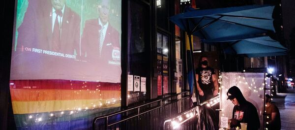 Трансляция первых дебатов действующего президента США Дональда Трампа и кандидата в президенты США Джо Байдена на мониторе у входа в бар в верхнем Вест-Сайде в Манхэттене - Sputnik Молдова