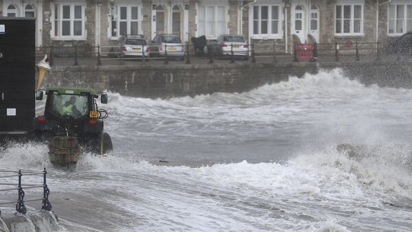 Трактор устанавливает временную защиту от наводнений на набережной британского города Суонедж  - Sputnik Молдова