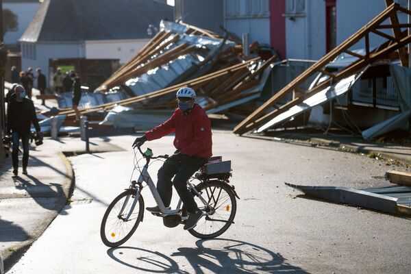 Ciclist pe fundalul acoperișului școlii din orașul Vannes, care s-a prăbușit în urma impactului uraganului Alex din Bretania franceză - Sputnik Moldova-România