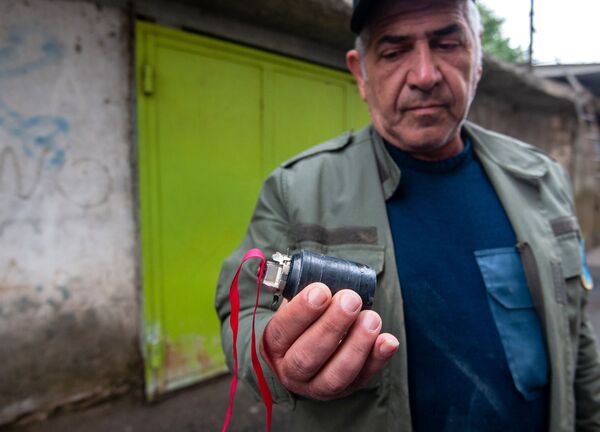 Мужчина держит в руке кассетный (кластерный) боеприпас, найденный после ночных обстрелов Степанакерта - Sputnik Молдова