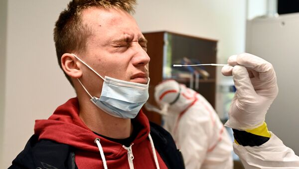 Медицинский работник берет образец мазка у человека на участке тестирования COVID-19 в Оравски-Подзамок, Словакия - Sputnik Молдова