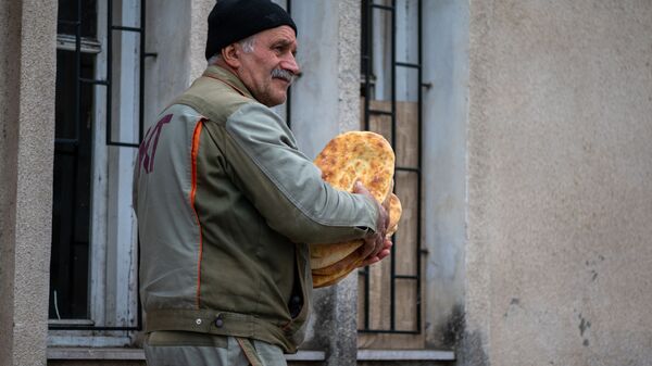 Мужчина со свежим хлебом на одной из улиц Степанакерта - Sputnik Moldova-România