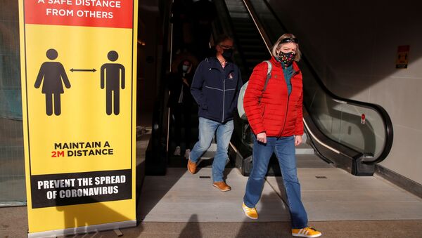 Люди в защитных масках проходят мимо знака социального дистанцирования в Ковентри, Великобритания - Sputnik Молдова