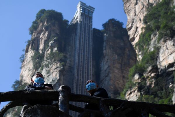 Two tourists wearing face masks look out in front of the Bailong Elevator in Zhangjiajie National Forest Park, China's Hunan province. - Sputnik Moldova