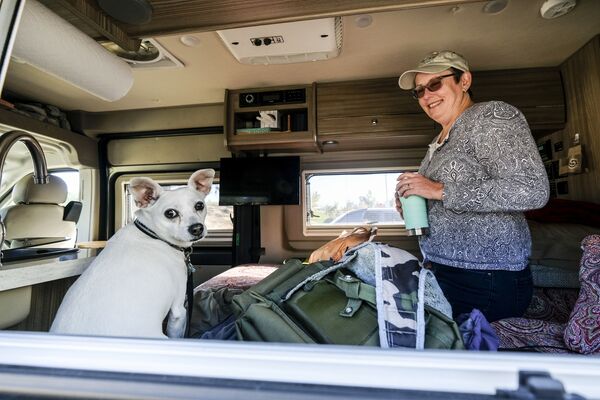 Женщина с собакой в своем автофургоне во временном пункте эвакуации Красного Креста в Оранж, штат Калифорния - Sputnik Молдова