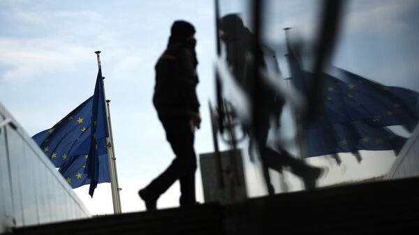 Пешеход идет под флагами ЕС у штаб-квартиры ЕС в Брюсселе - Sputnik Молдова