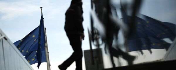 Пешеход идет под флагами ЕС у штаб-квартиры ЕС в Брюсселе - Sputnik Moldova