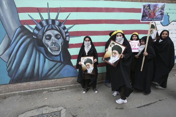 Female Iranian school girls stand in front of a satirized drawing of the Statue of Liberty, painted on the wall of the former US Embassy in Tehran, Iran, as they hold posters of supreme leader Ayatollah Ali Khamenei, and anti-US and anti-Israel placards, in an annual state-backed rally, on Friday, Nov. 4, 2011, marking anniversary of the seizure of the US Embassy by militant students on Nov. 4, 1979, when militant Iranian students who believed the embassy was a center of plots against the Persian country held 52 Americans hostage for 444 days. The US severed diplomatic ties in response, and the two countries have not had formal relations since.  - Sputnik Молдова