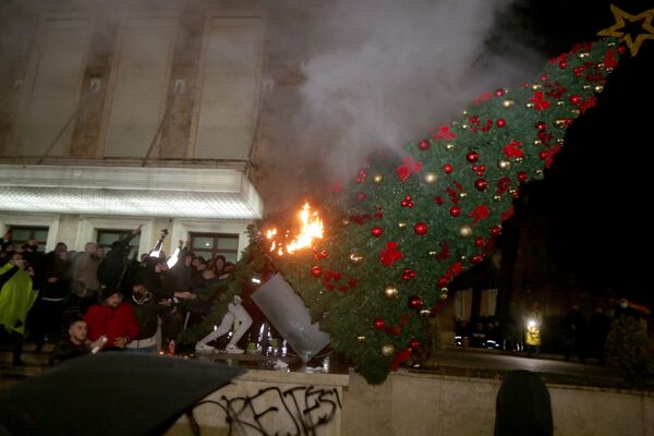 Протестующие сжигают рождественскую елку перед зданием премьер-министра Албании во время столкновений в Тиране - Sputnik Молдова