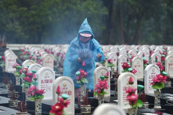 Посетитель зажигает ароматические палочки на кладбище мучеников Truong Son, Вьетнам - Sputnik Молдова