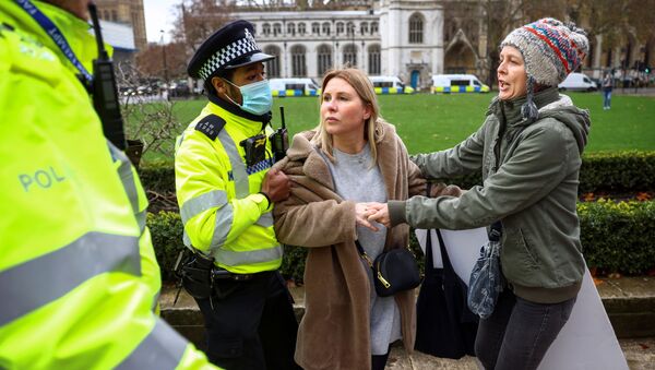 Полицейский пытается задержать активистку демонстрации против вакцинации в Лондоне - Sputnik Moldova-România