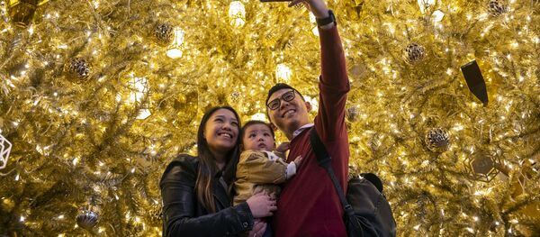 Молодые люди с ребенком фотографируются перед золотыми рождественскими елками в торговом центре в Гонконге Молодые люди с ребенком фотографируются перед золотыми рождественскими елками в торговом центре в Гонконге - Sputnik Молдова