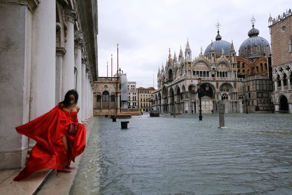 A woman stands in flooded St. Mark's Square during high tide as the flood barriers known as Mose are not raised, in Venice, Italy, December 8, 2020 - Sputnik Молдова