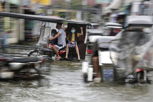 Residents wearing masks to prevent the spread of the coronavirus ride motorcycles as they negotiate a flooded road due to Typhoon Molave in Pampanga province, northern Philippines on Monday, Oct. 26, 2020. A fast moving typhoon has forced thousands of villagers to flee to safety in provinces - Sputnik Молдова