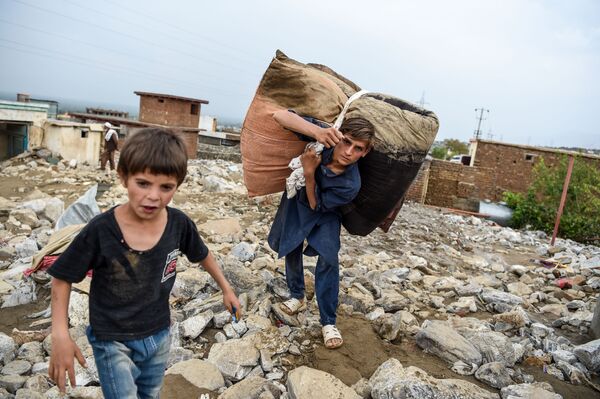 Молодые люди спасают остатки вещей из развалин домов после внезапного наводнения в Чарикаре, провинция Парван, Афганистан - Sputnik Moldova-România