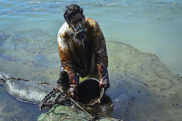 A man scoops leaked oil from the vessel MV Wakashio, belonging to a Japanese company but Panamanian-flagged, that ran aground near Blue Bay Marine Park off the coast of south-east Mauritius on August 8, 2020. - France on August 8, 2020 dispatched aircraft and technical advisers from Reunion to Mauritius after the prime minister appealed for urgent assistance to contain a worsening oil spill polluting the island nation's famed reefs, lagoons and oceans. Rough seas have hampered efforts to stop fuel leaking from the bulk carrier MV Wakashio, which ran aground two weeks ago, and is staining pristine waters in an ecologically protected marine area off the south-east coast. - Sputnik Молдова