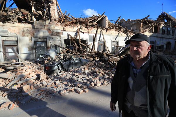 A man stands on a street next to destroyed houses on a street after an earthquake in Petrinja, Croatia December 29, 2020.  - Sputnik Молдова