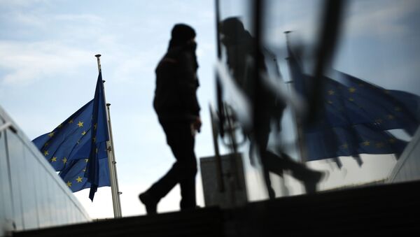 Пешеход идет под флагами ЕС у штаб-квартиры ЕС в Брюсселе - Sputnik Moldova-România