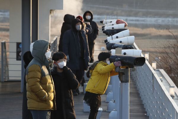 Persoane care poartă măști de protecție privesc în binoclu lângă granița cu Coreea de Nord și Coreea de Sud - Sputnik Moldova-România