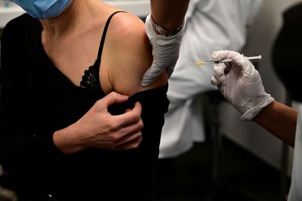 Женщина получает вакцину от COVID-19 во время кампании вакцинации медицинских работников в центре вакцинации в Париже - Sputnik Moldova