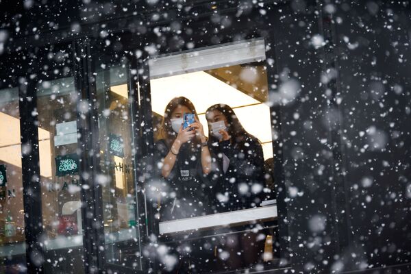 Девушки фотографируют снегопад в Сеуле  - Sputnik Молдова
