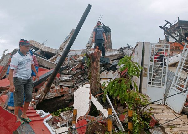 Жители осматривают поврежденные землетрясением дома в Мамуджу, Сулавеси, Индонезия - Sputnik Moldova-România