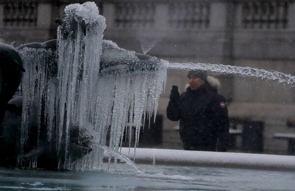 Мужчина фотографирует покрытую льдом статую на Трафальгарской площади в Лондоне - Sputnik Moldova-România