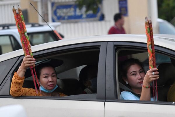 Женщины с ароматическими палочками в машине во время празднования Нового года по лунному календарю в Такмау, Камбоджа - Sputnik Молдова