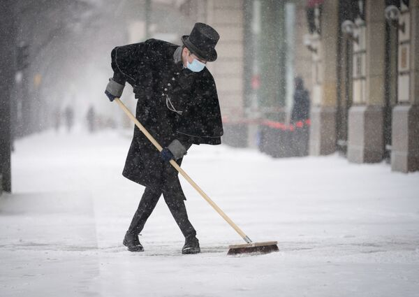 Сотрудник отеля Adlon чистит тротуар от снега на Парижской площади в Берлине - Sputnik Молдова