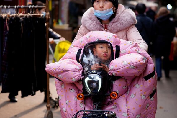 Женщина везет ребенка в коляске на улице в Ухане - Sputnik Молдова