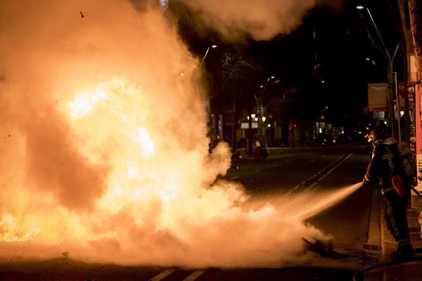 Сотрудник пожарной службы тушит горящий скутер на одной из улиц Барселоны, где проходит акция протеста в поддержку рэпера Пабло Аселя - Sputnik Moldova-România