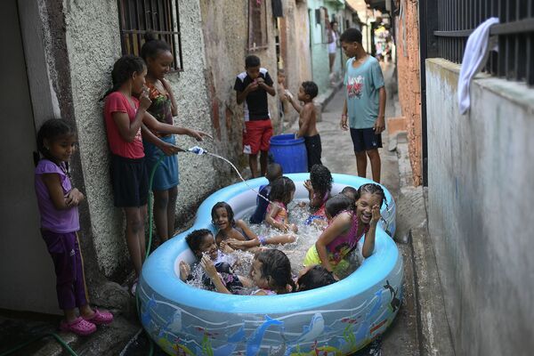 Дети играют в надувном бассейне на одной из улиц Каракаса, Венесуэла - Sputnik Молдова