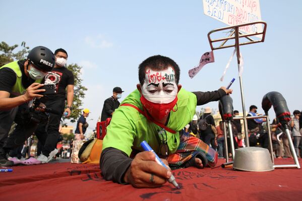 Протестующий пишет на ткани во время акции протеста в Бангкоке - Sputnik Молдова