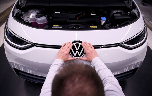 Рабочий устанавливает логотип VW на электромобиле Volkswagen ID.3 на сборочном конвейере автозавода Volkswagen - Sputnik Молдова