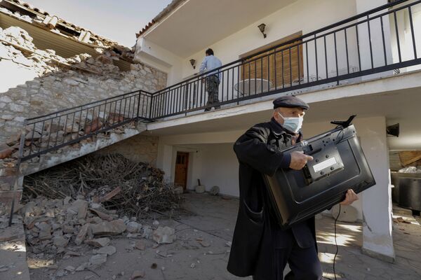 Мужчина с телевизором у поврежденного дома вследствие землетрясения в Греции  - Sputnik Молдова