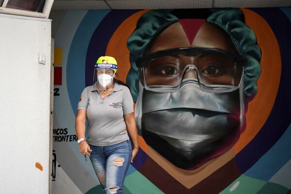 Медицинский работник в защитной маске у граффити в Каракасе - Sputnik Молдова