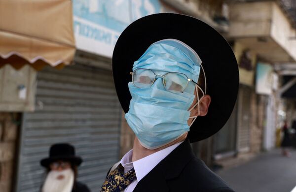 Мужчина в защитных масках на лице во время празднования Пурима в Иерусалиме - Sputnik Молдова