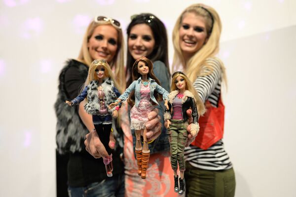 Модели позируют с куклами Барби, одетыми в похожие наряды, на стенде Mattel на Международной выставке игрушек в Нюрнберге - Sputnik Молдова