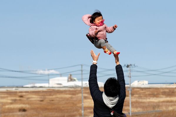 Потерявший родных во время землетрясения 2011 года отец с ребенком в префектуре Фукусима  - Sputnik Молдова