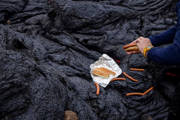 Мужчина готовит хот-доги на вулканическом участке на полуострове Рейкьянес после извержения вулкана в Исландии - Sputnik Молдова